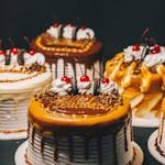 A mouthwatering variety of drip cakes perfect for birthdays or celebrations, adorned with cherries and chocolate.