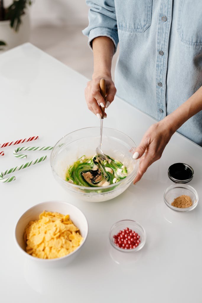 A woman prepares festive cookies by mixing ingredients in a bowl, creating a colorful kitchen scene.