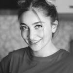 Monochrome portrait of a smiling woman with hair buns, exuding happiness.